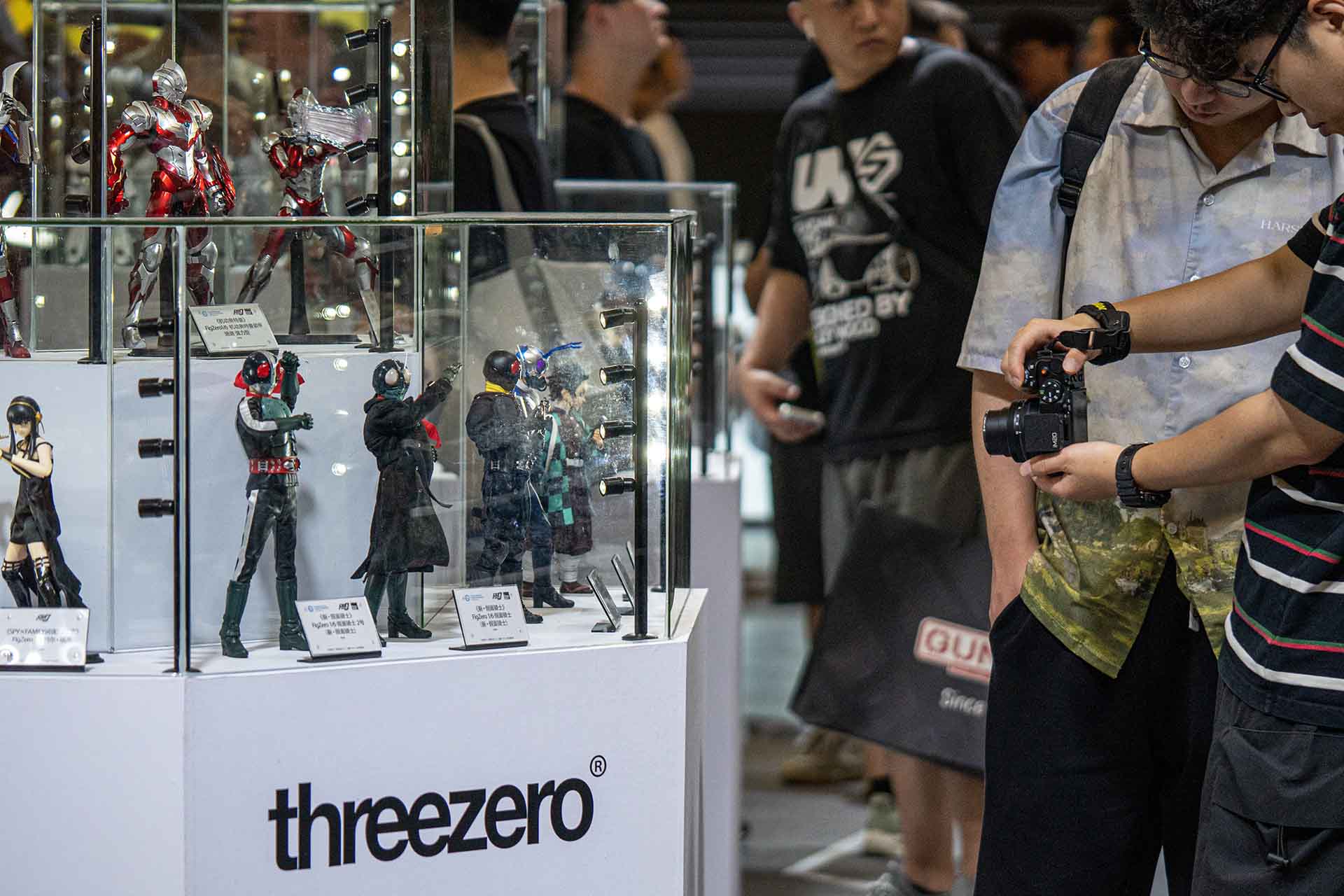 Boy photographing model figures at Chinajoy with enthusiasm