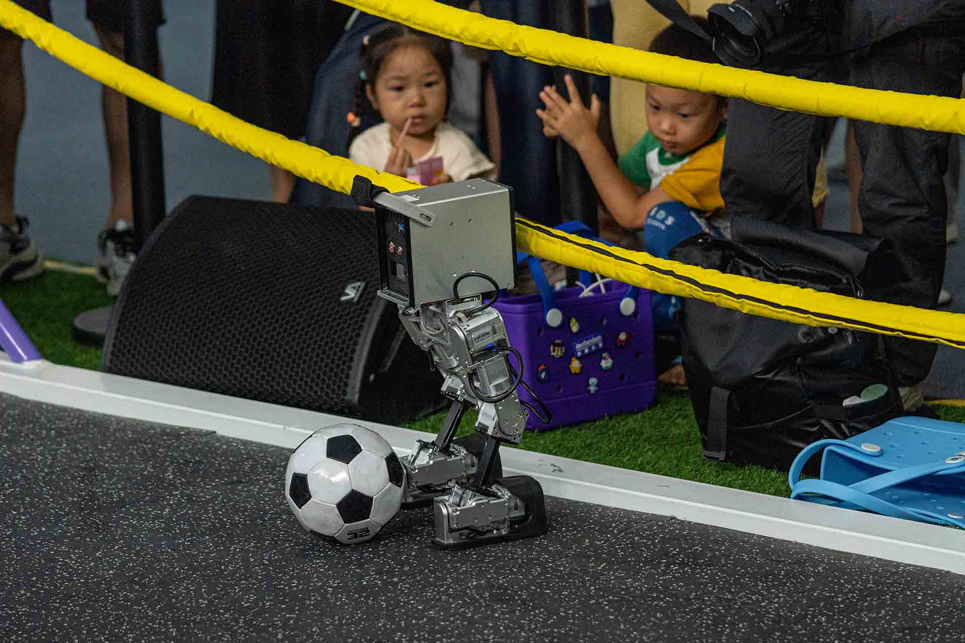 Robot playing soccer in front of cheering crowd