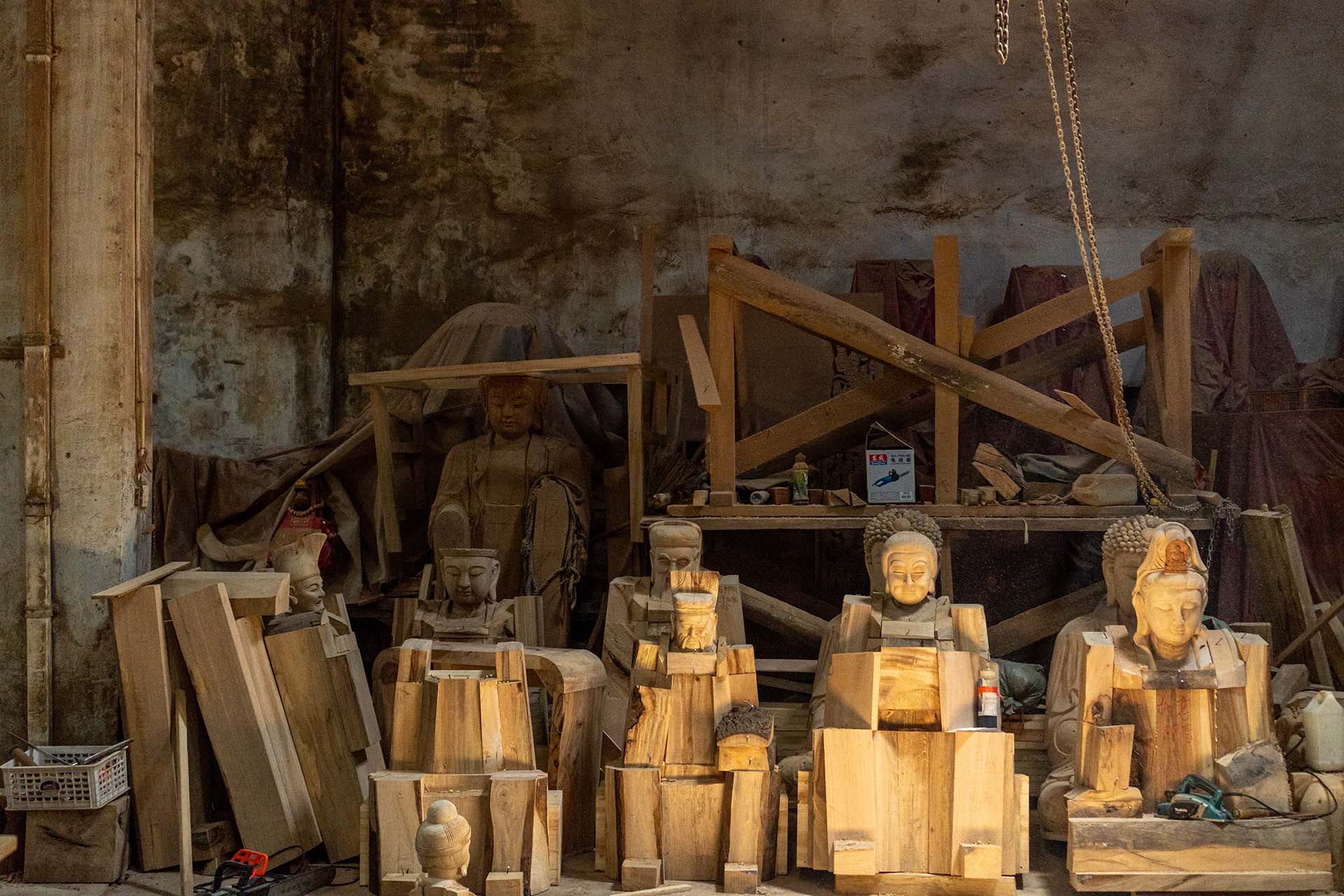 Stacked wooden Buddha statues inside workshop