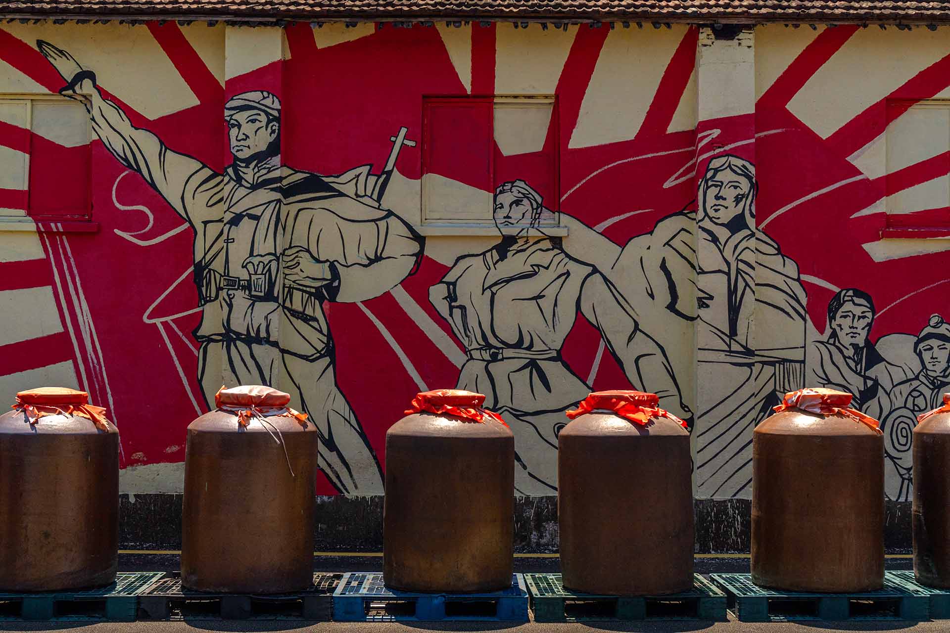 Baijiu containers displayed in front of vintage propaganda graffiti