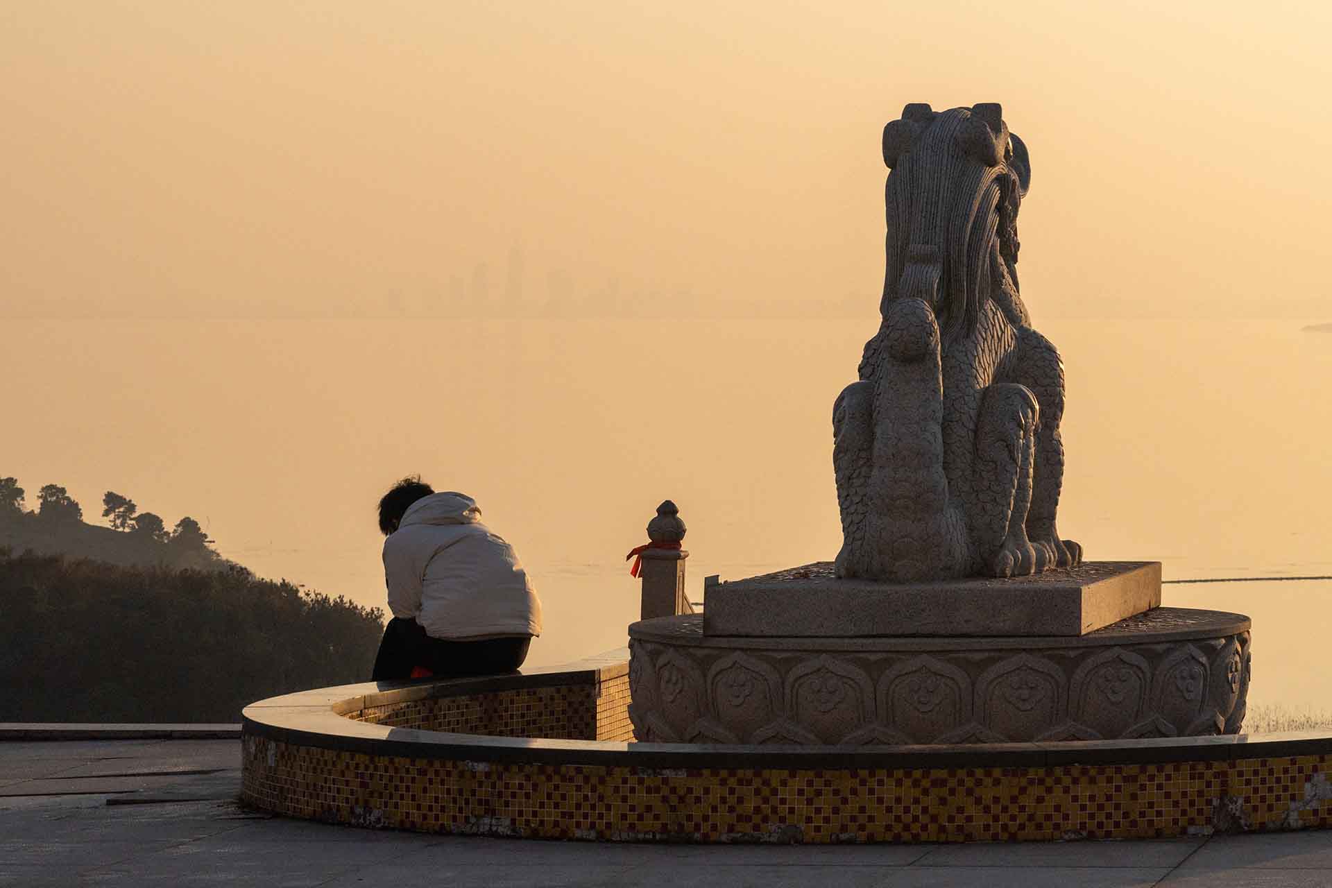 Boy looking at phone with Taihu Lake sunset background